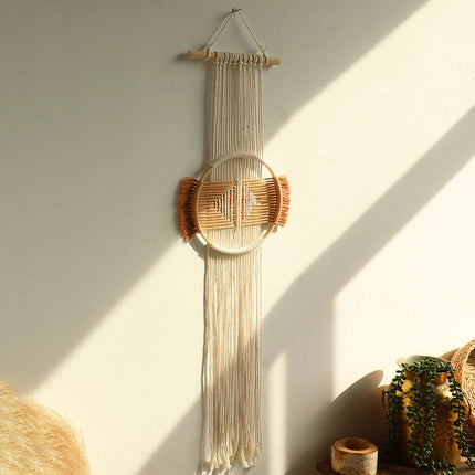 Tenture murale macramé rond en coton écru à motif géométrique terracotta, suspendue sur un mur baigné de lumière