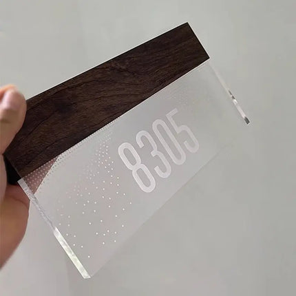 Détail de la plaque en acrylique givré et du bandeau bois foncé du numéro lumineux tenu en main