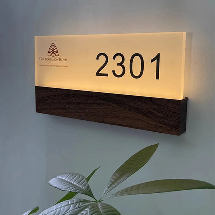 Numéro lumineux LED 2301 allumé en blanc chaud sur un mur, finition acrylique givré et bois foncé
