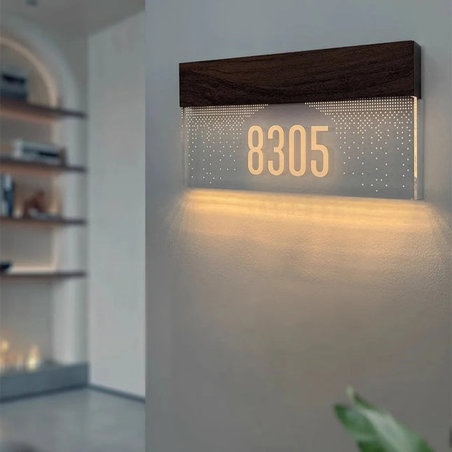 Numéro de maison lumineux LED 8305 en acrylique givré et bois foncé, allumé en blanc chaud sur un mur d'entrée