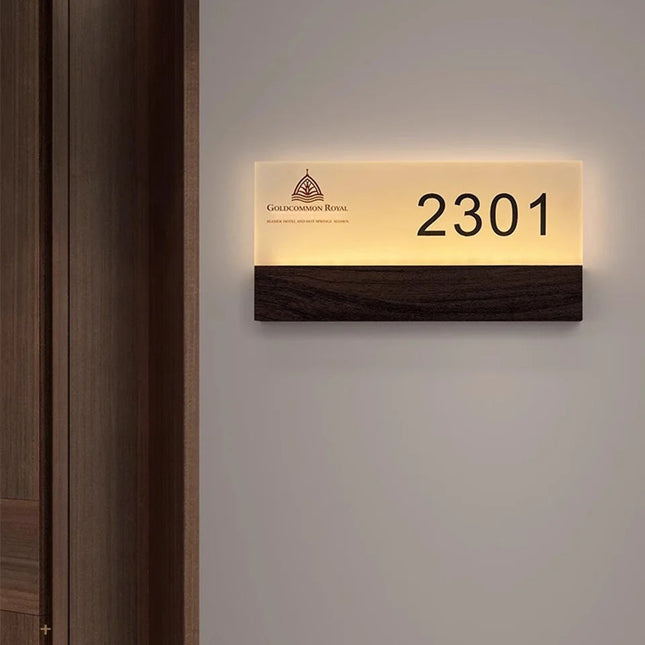 Numéro de porte lumineux LED personnalisé avec logo, plaque acrylique et bandeau bois foncé posé sur une porte