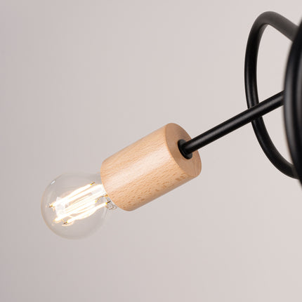 plafonnier 3 bras bouclés en bois et métal noir, vue sur fond coloré