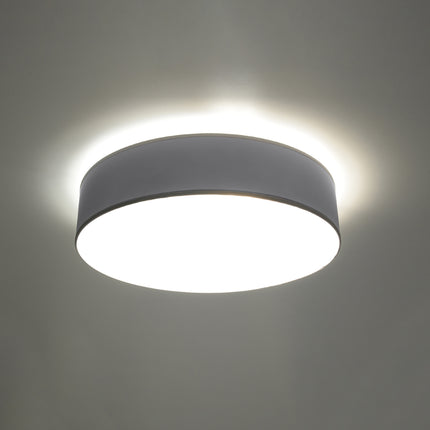 Plafonnier Arène rond gris allumé au plafond, lumière chaude diffusée par le diffuseur opalin