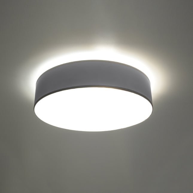 Plafonnier Arène rond gris allumé au plafond, lumière chaude diffusée par le diffuseur opalin