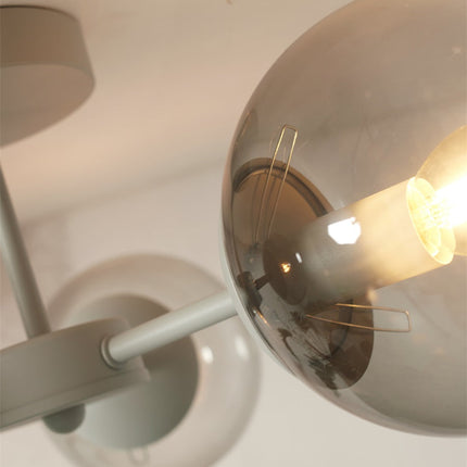 Gros plan sur le globe en verre gris fumé et l'ampoule du plafonnier Aspen