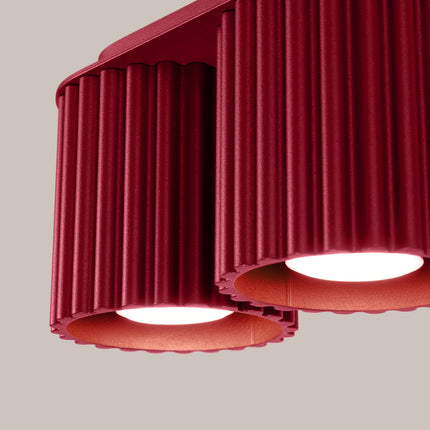 Détail des deux tubes rainurés bordeaux du plafonnier Aura et de leur faisceau lumineux