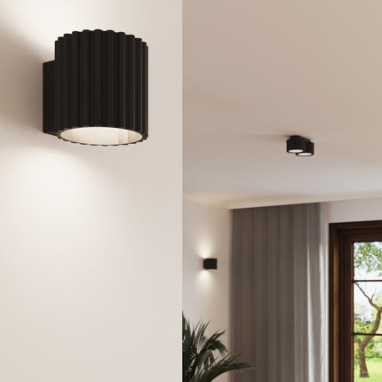 Plafonnier Aura noir cannelé installé au mur et au plafond dans un salon