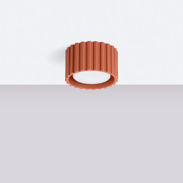 Plafonnier Aura rouge ocre fixé au plafond blanc d'un salon lumineux