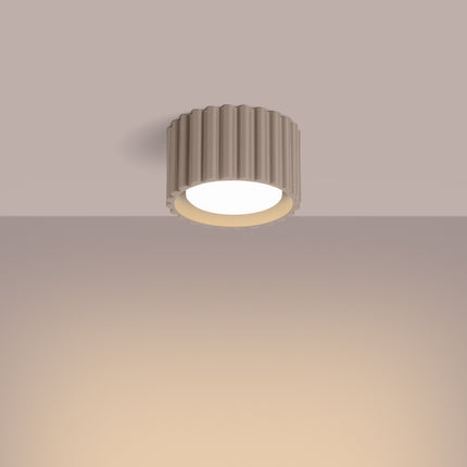 Plafonnier Aura taupe allumé diffusant une lumière chaude au plafond
