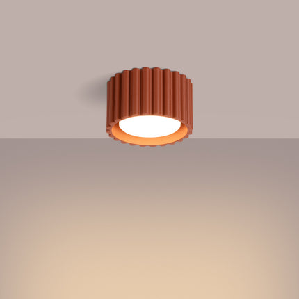Plafonnier Aura terracotta allumé au plafond, lumière chaude et diffuse