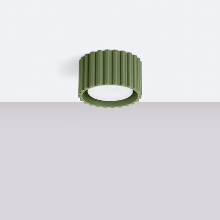 Plafonnier Aura vert olive fixé au plafond blanc d'un intérieur épuré