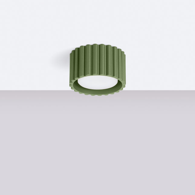 Plafonnier Aura vert olive fixé au plafond blanc d'un intérieur épuré