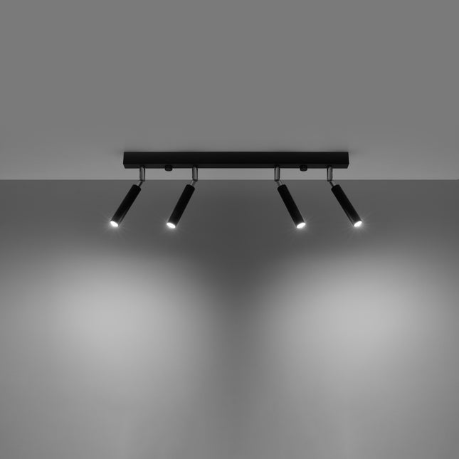 Plafonnier barre acier noir avec ses quatre spots orientables allumes projetant la lumiere