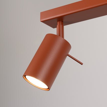 Plafonnier Barre 4 Spots Orientables Rouge Ocre, vue sur fond coloré