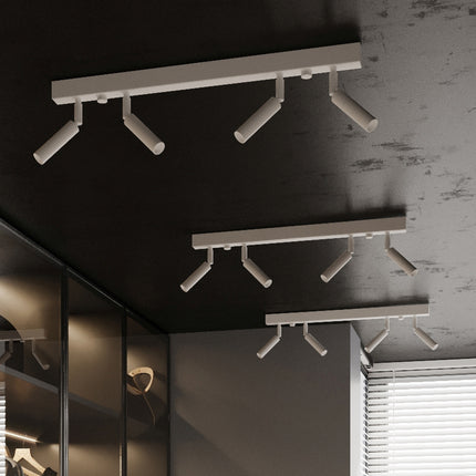 Plusieurs plafonniers barres blancs a spots orientables sur un plafond noir de dressing