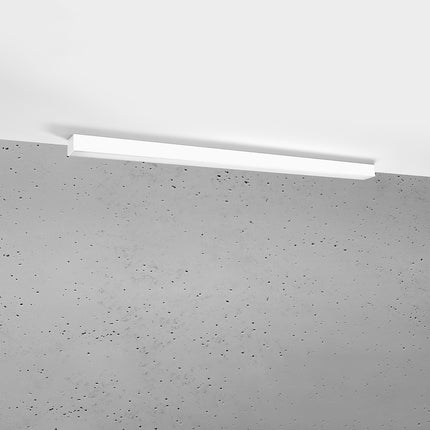 Plafonnier barre moderne LED blanc 118 cm installé au plafond au-dessus d'un mur de béton