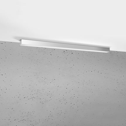 Plafonnier barre moderne LED gris 118 cm installé au plafond au-dessus d'un mur de béton