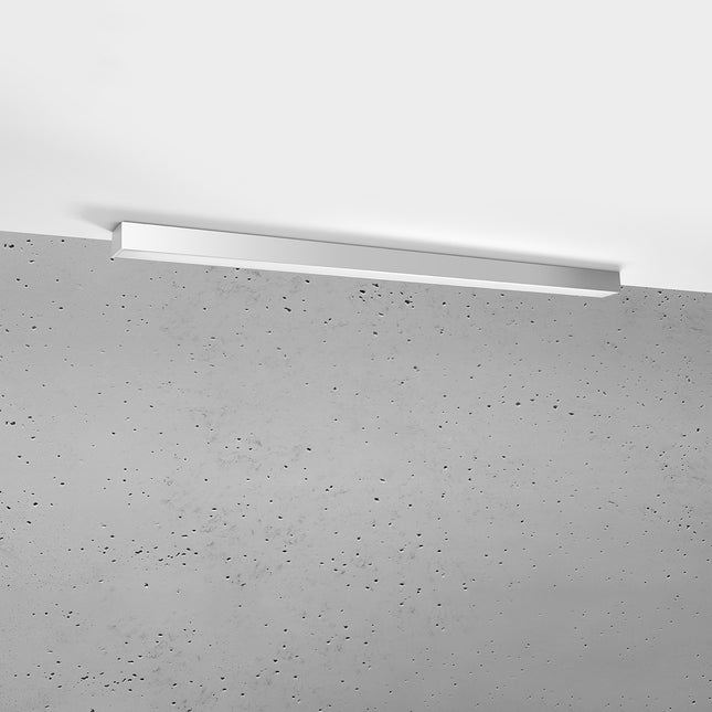 Plafonnier barre moderne LED gris 118 cm installé au plafond au-dessus d'un mur de béton