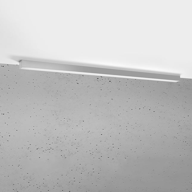 Plafonnier barre moderne LED gris 150 cm installé au plafond au-dessus d'un mur de béton