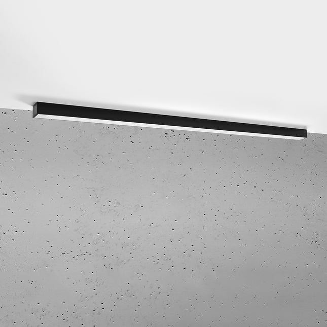 Plafonnier barre moderne LED noir 150 cm installé au plafond au-dessus d'un mur de béton