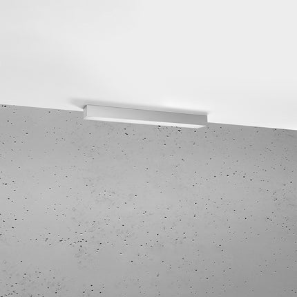 Plafonnier barre moderne LED gris installé au plafond au-dessus d'un mur de béton