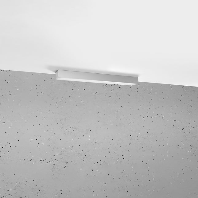 Plafonnier barre moderne LED gris installé au plafond au-dessus d'un mur de béton