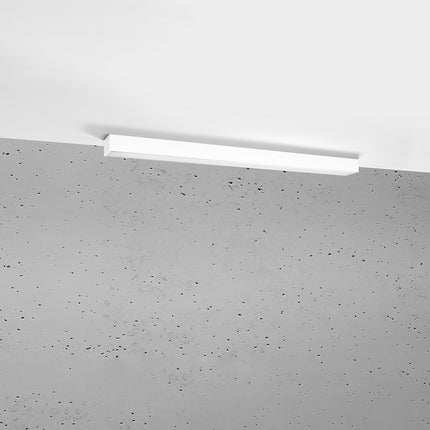 Plafonnier barre moderne LED blanc 90 cm installé au plafond au-dessus d'un mur de béton