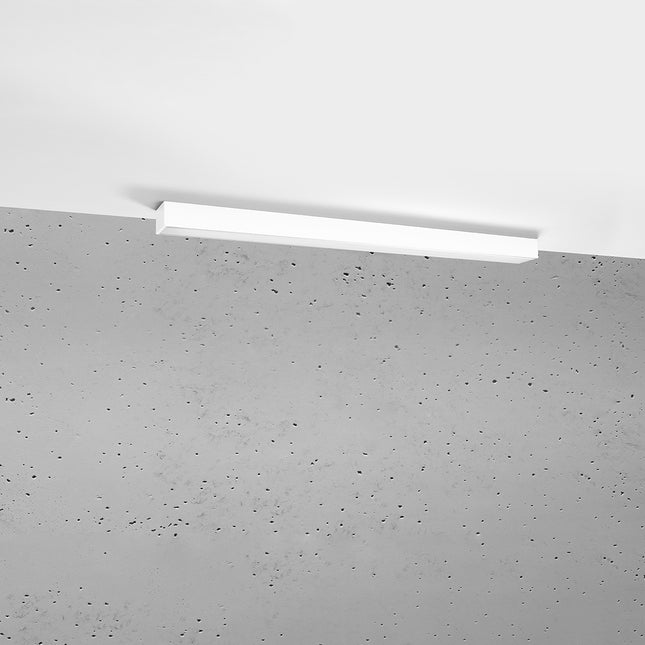 Plafonnier barre moderne LED blanc 90 cm installé au plafond au-dessus d'un mur de béton