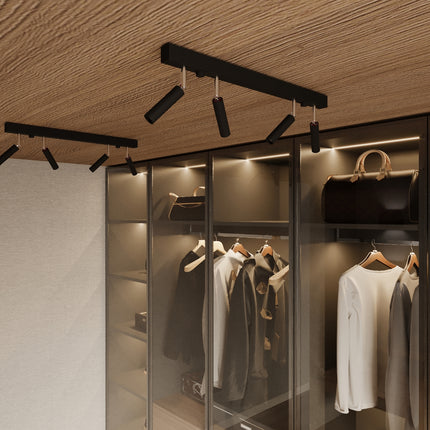 Barre de spots noirs orientables eclairant une penderie vitree dans un dressing contemporain