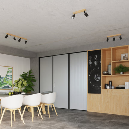 Salle à manger avec plafonniers bois et métal noir orientés sur différents espaces