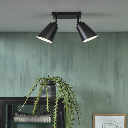 Plafonnier Bremen noir mat installé au plafond au dessus d'un meuble avec plante suspendue