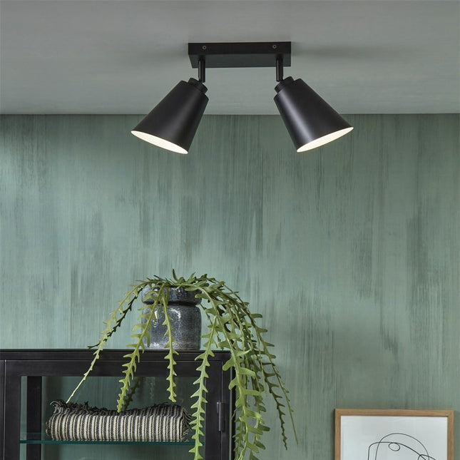 Plafonnier Bremen noir mat installé au plafond au dessus d'un meuble avec plante suspendue