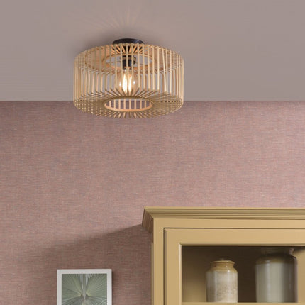 Round Bromo ceiling light in braided natural bamboo, lit, hanging on the ceiling of a living room with pink tones