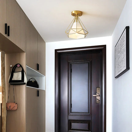 Plafonnier cage diamant en fer doré au-dessus d'une porte d'entrée sombre