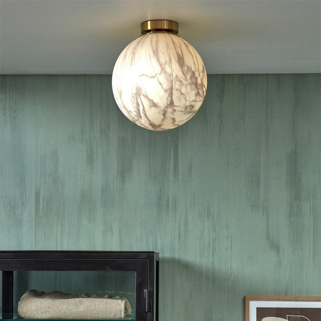 Vue d'ensemble du plafonnier Carrara globe marbre et doré au-dessus d'un meuble bas