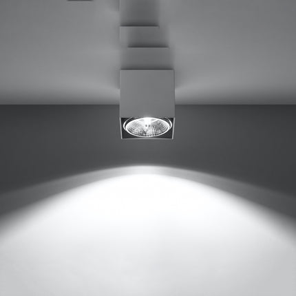 Plafonnier carré blanc allumé projetant un faisceau lumineux net vers le sol sur fond gris