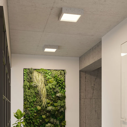 Détail d'un plafonnier Carré Brut en béton allumé dans un couloir