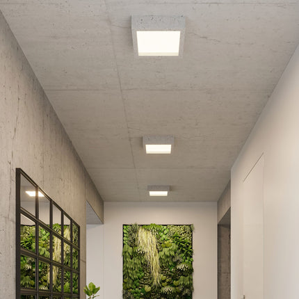 Vue d'ensemble d'un couloir éclairé par des plafonniers Carré Brut en béton