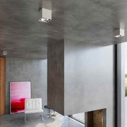 Plafonniers carrés gris allumés dans un intérieur béton contemporain lumineux