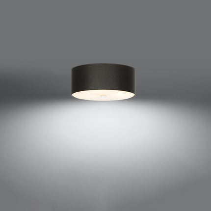 Plafonnier Cercle Plein noir 30 cm vu de trois quarts, tambour en tissu et diffuseur en verre éclairé.