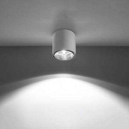 Plafonnier circulaire blanc allumé projetant un faisceau lumineux net sur le mur et le sol