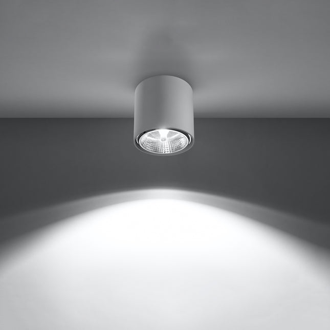Plafonnier circulaire blanc allumé projetant un faisceau lumineux net sur le mur et le sol