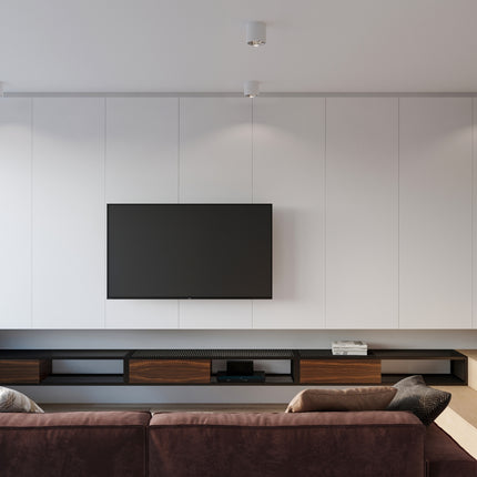 Deux plafonniers circulaires blancs au plafond d'un salon minimaliste avec téléviseur mural