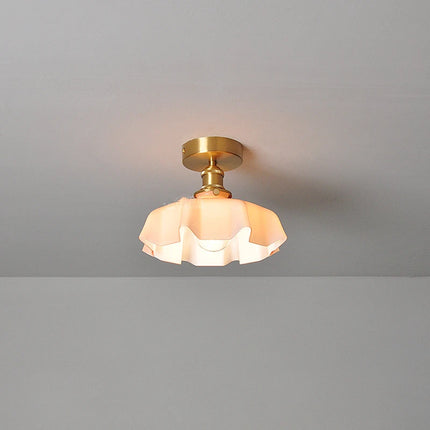 Plafonnier corolle en verre rose poudré et cuivre installé au ras du plafond dans un intérieur épuré