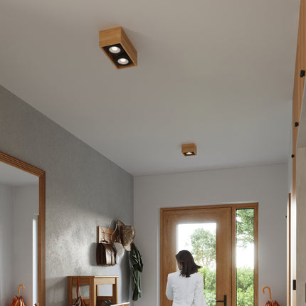 Gros plan d'un plafonnier cube bois naturel fixe au plafond, spot GU10 allume