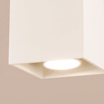 Plafonnier Cube LED beige clair sur fond coloré, vue de trois quarts