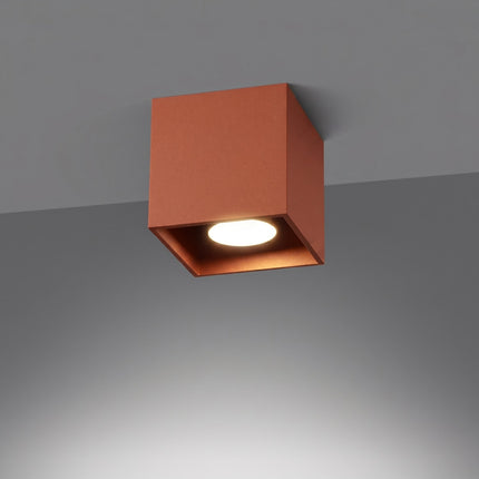 Plafonnier Cube LED ocre rouge allumée, faisceau net sur le mur