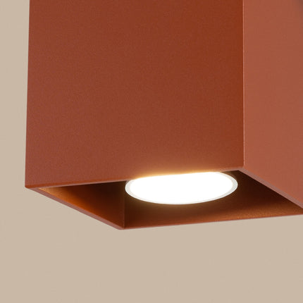 Plafonnier Cube LED ocre rouge sur fond coloré, vue de trois quarts