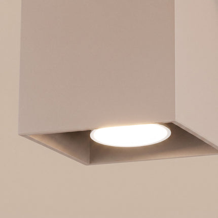 Plafonnier Cube LED taupe sur fond coloré, vue de trois quarts