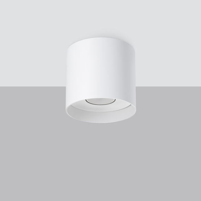 Plafonnier cylindrique blanc vu en saillie sur un plafond, ambiance intérieure claire
